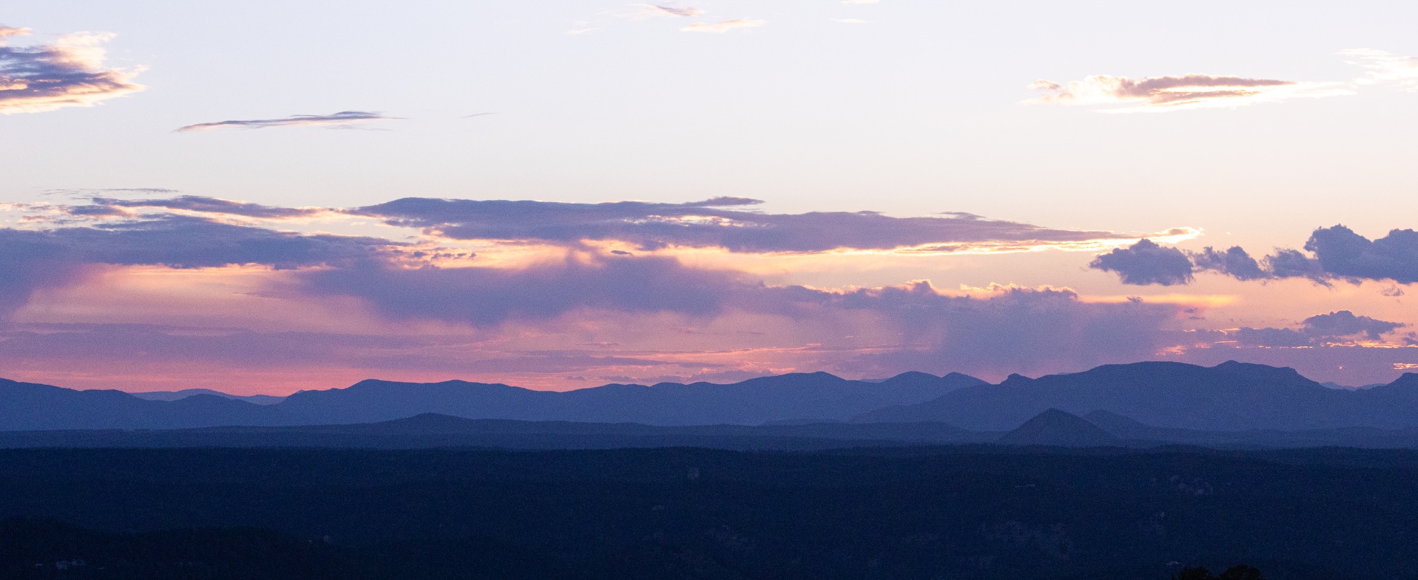Layered mountains beneath a violet and peach sunset